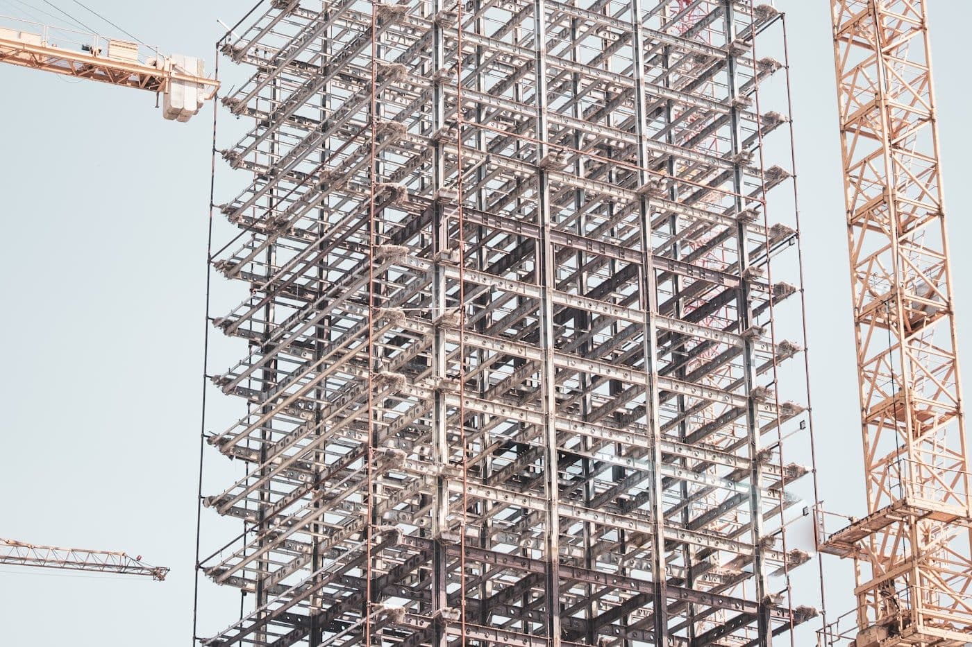 Steel frame of a building under construction between two tower cranes