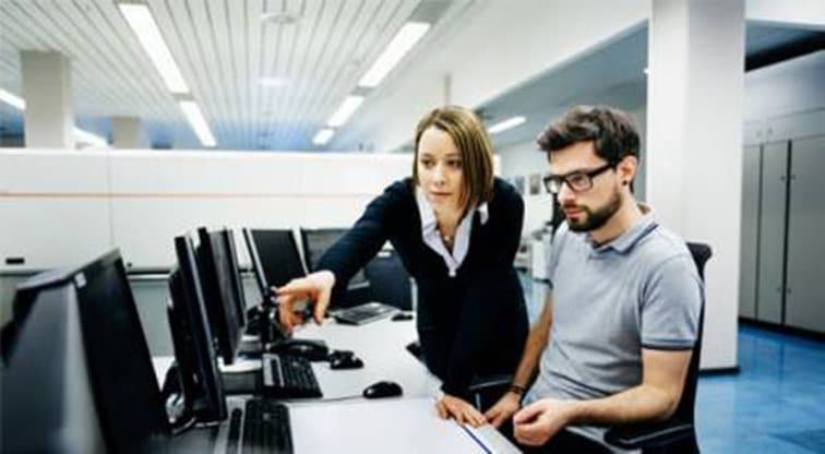 Two colleagues reviewing security settings at a row of workstations