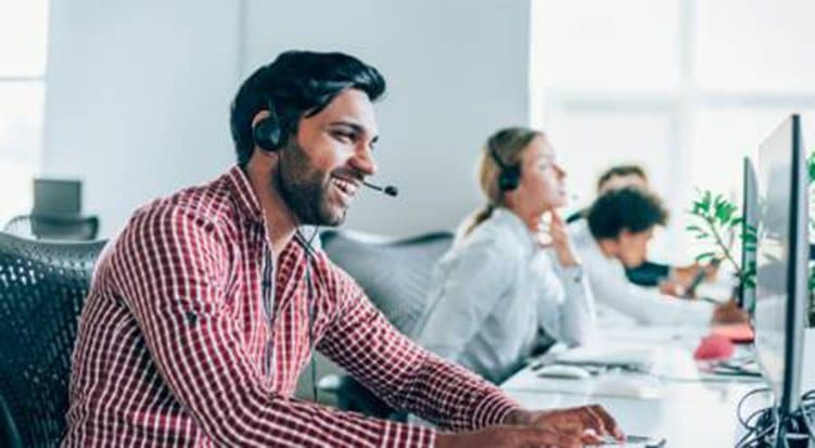 A support technician wearing a headset taking a call at their desk