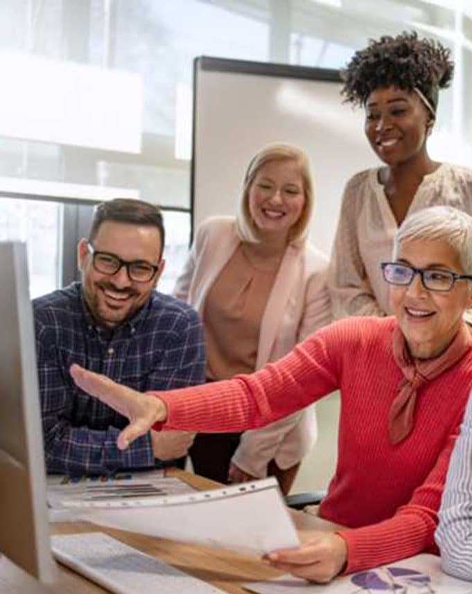 Colleagues gathered around a monitor reviewing work together